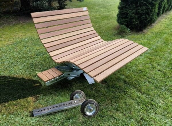 Ein geschwungenes Waldsofa aus Bangkirai-Holz mit ausziehbarem Tisch und separater Transportvorrichtung mit zwei Rädern.